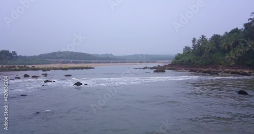 Panorama Of Galgibaga Beach With Splashing Waves Into Outcrops And Lush Mountains At Canacona, South Goa, India. - Aerial Wide Shot photo