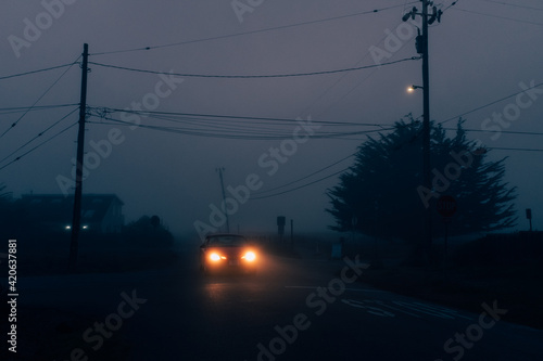 A car driving through a small neighborhood on a foggy evening photo