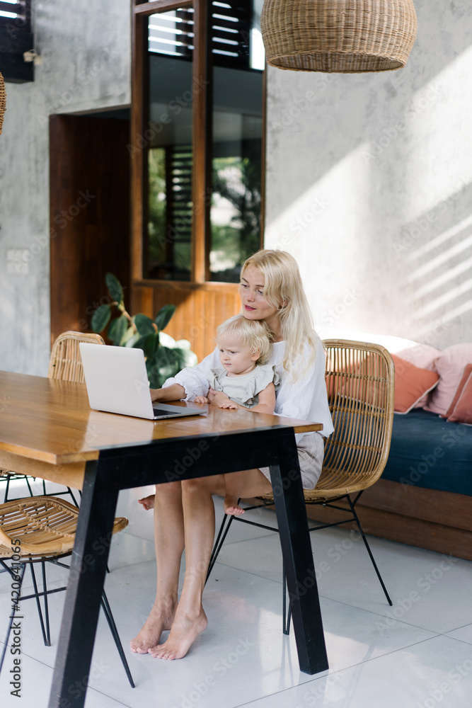 Woman with little child working remotely at home Woman with little child working remotely at home