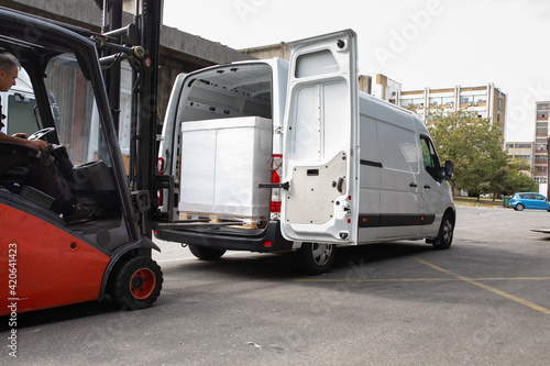 The worker transports freight into a van using a forklift photo