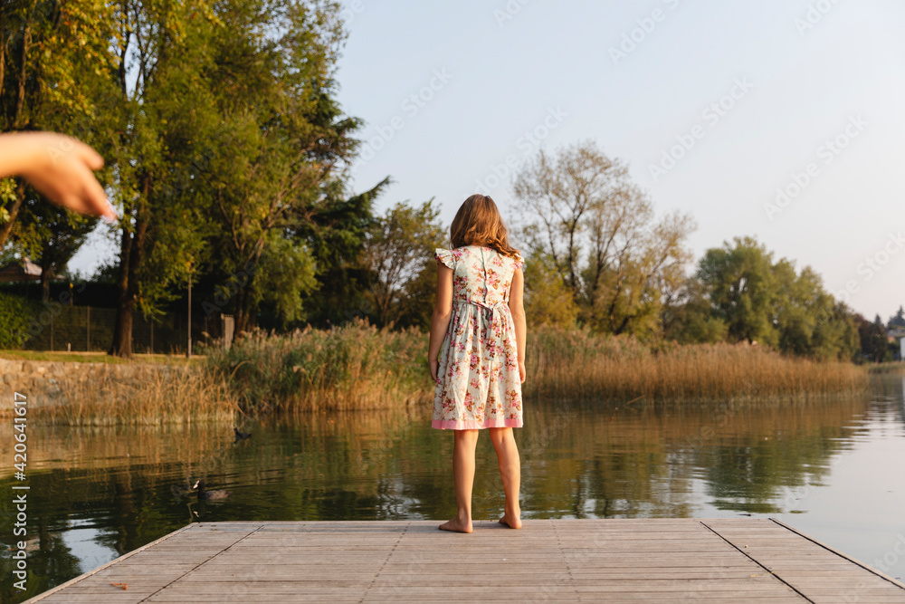 Little girl standing on a wooden pier on the lake Stock Photo | Adobe Stock
