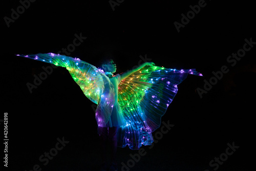 Night photo of girl in light-up LED wing costume