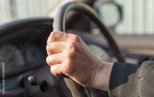 Selective focus of male hands on the steering wheel driving a car. Travel background