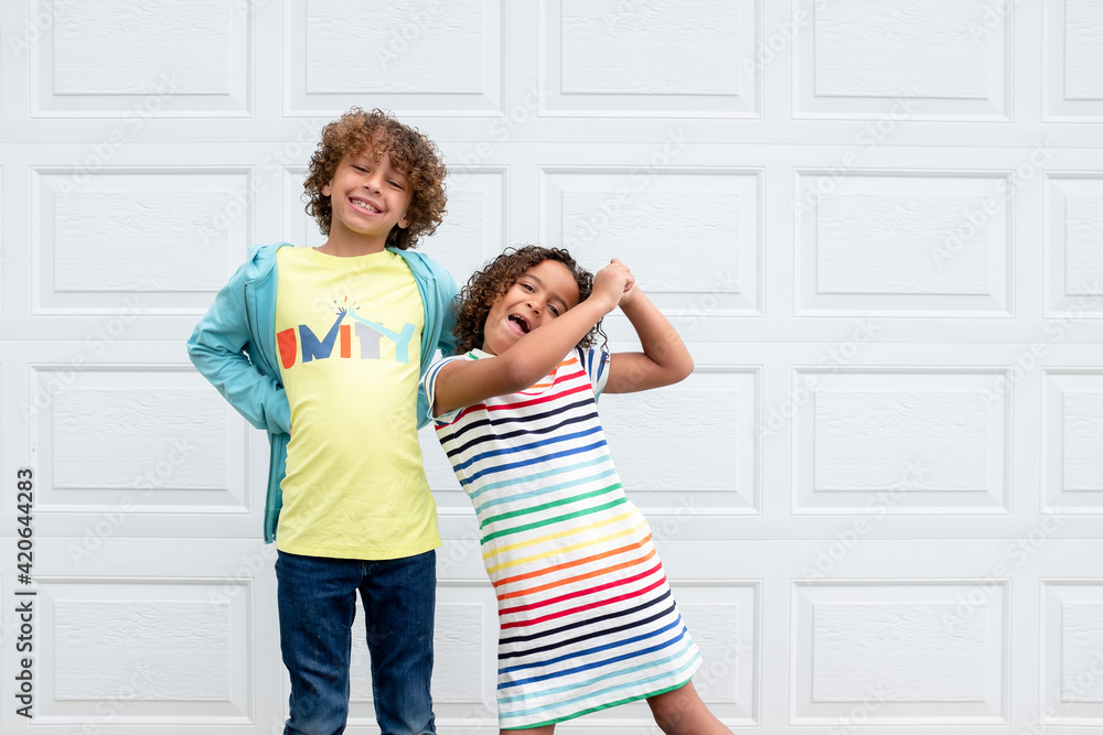 Multiracial siblings laughing and dancing in front of garage Multiracial siblings laughing and dancing in front of garage