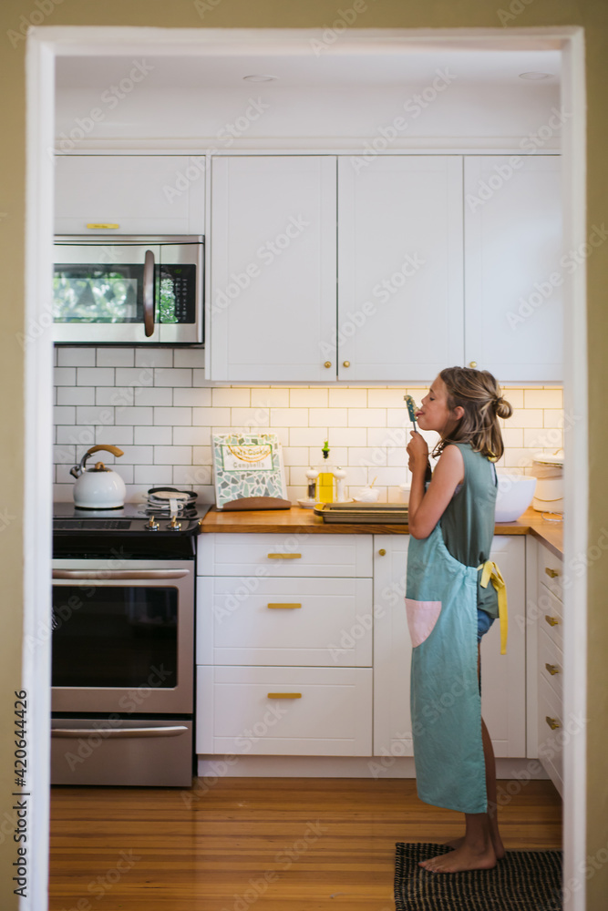 Young girl baking by herself in the kitchen and taste testing th Young girl baking by herself in the kitchen and taste testing th