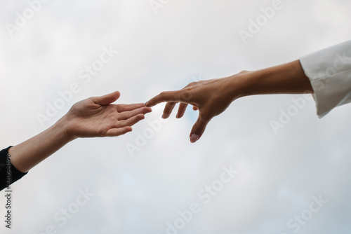 two hands touche each other in front of the sky photo