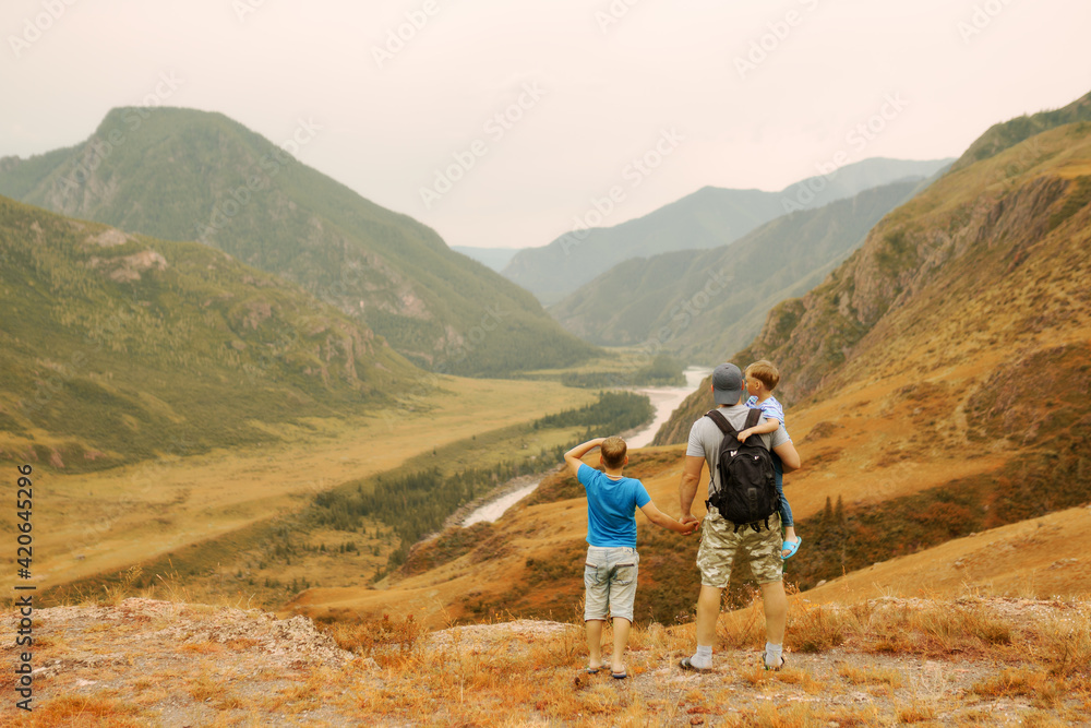 Father and sons stand at the edge of the mountain and look into the distance