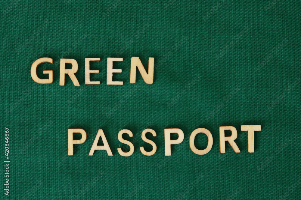 Obraz premium COVID vaccine passport wooden alphabet letters on a green fabric. Green Passport.