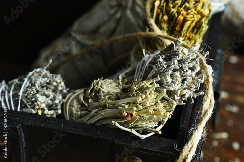 A top view image of several sage smudge sticks in a dark wooden trunk. 