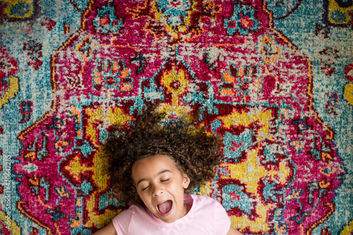 Laughing girl laying on a colorful rug photo