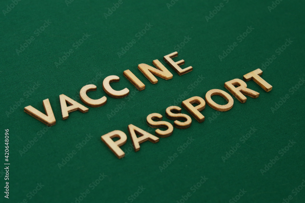 Obraz premium COVID vaccine passport wooden alphabet letters on a green fabric. Green Passport.