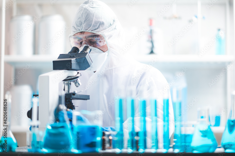 Scientist analyzing microscope slide at laboratory. Young woman technician is examining a histological sample, a biopsy in the laboratory of cancer research Scientist analyzing microscope slide at laboratory. Young woman technician is examining a histological sample, a biopsy in the laboratory of cancer research