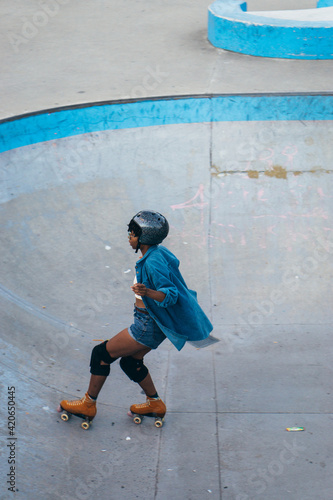 Cool African American woman drives roller skates in an open area photo