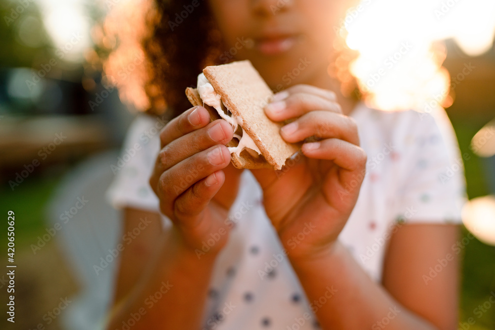 Girl eating s'more in golden sunlight Girl eating s'more in golden sunlight