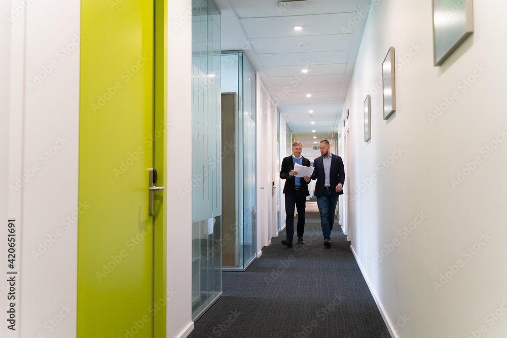 Colleagues Walking At Office Corridor Colleagues Walking At Office Corridor
