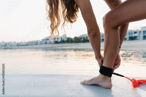 A woman fixing her leg on the paddle board photo