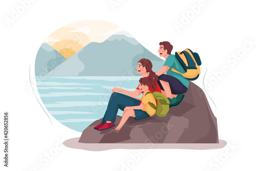 A small family is watching the sunset on the rock.