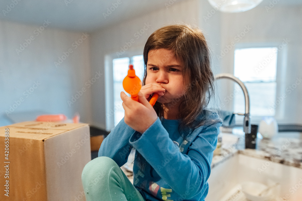 Young girl trying to blow up a balloon.