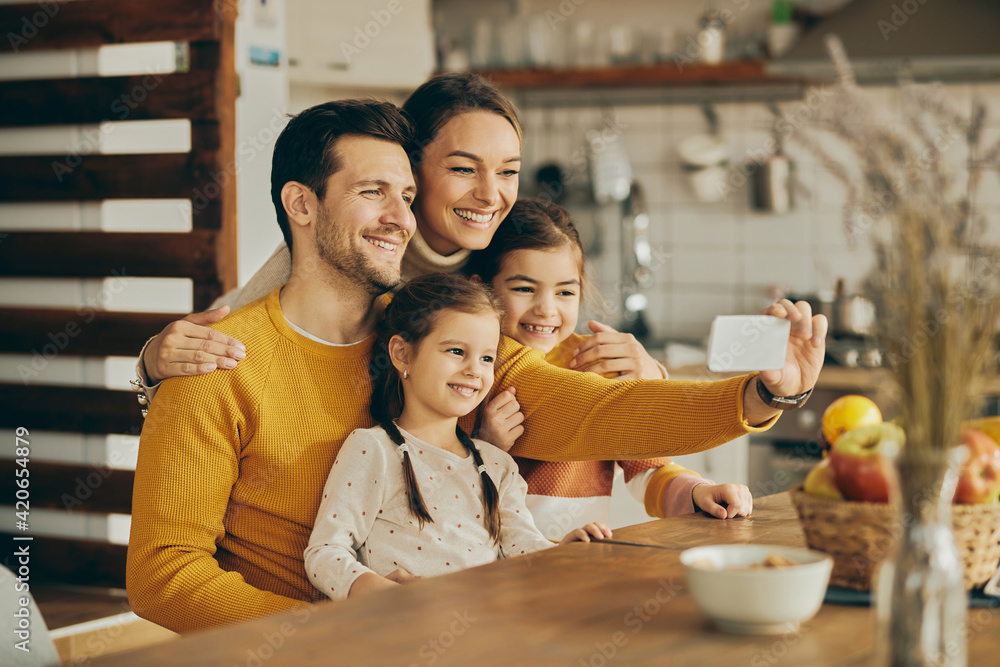 Obraz premium Happy family having fun while taking selfie with cell phone at home.