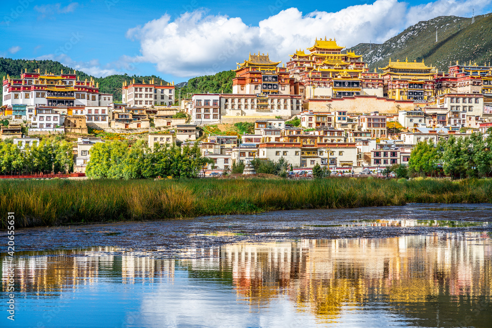 Songzanlin monastery with beautiful water reflection on lake during sunny day Shangri-La Yunnan China