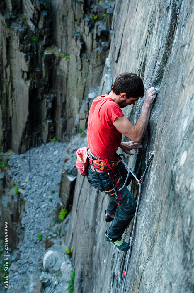 Climber balancing foot in vertical quarry wall Climber balancing foot in vertical quarry wall