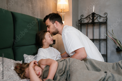 Father kissing sleeping daughters in evening