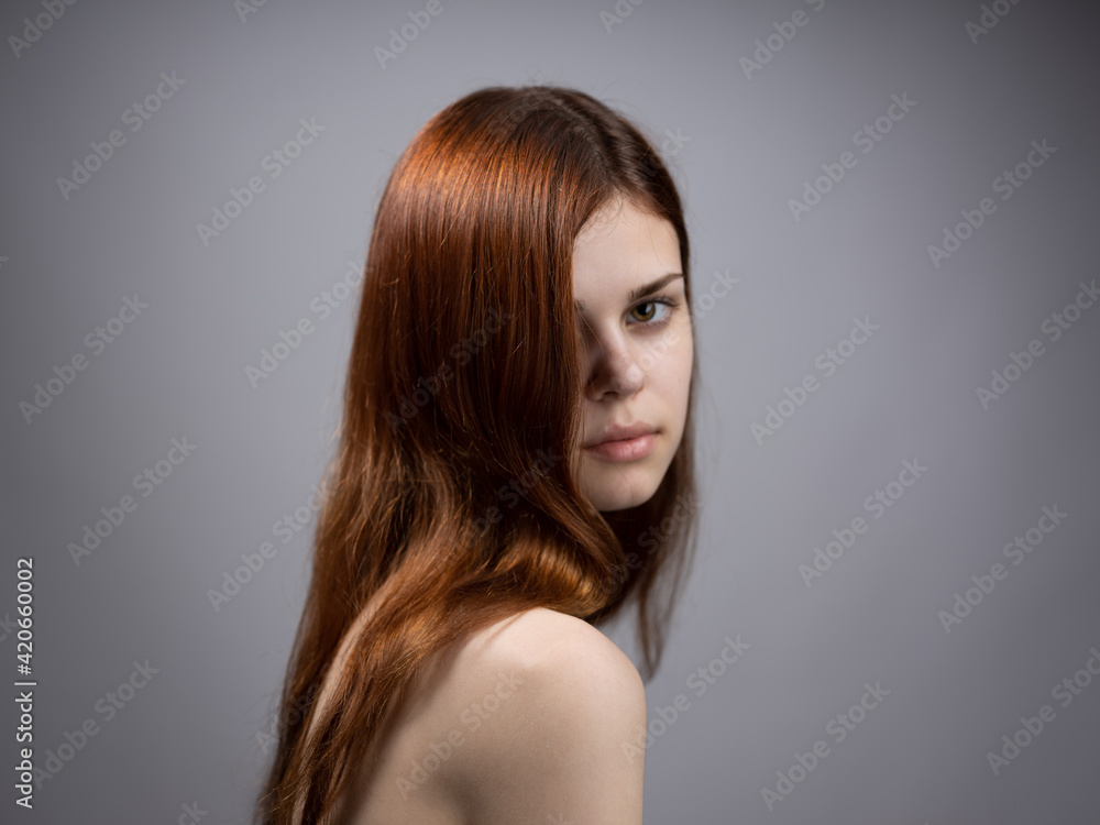 Beautiful woman with loose red hair on a gray background bared shoulders portrait Beautiful woman with loose red hair on a gray background bared shoulders portrait