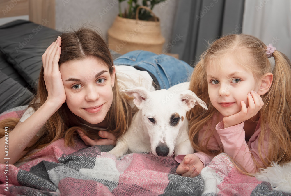 Teenage girl and child playing with their dog Teenage girl and child playing with their dog