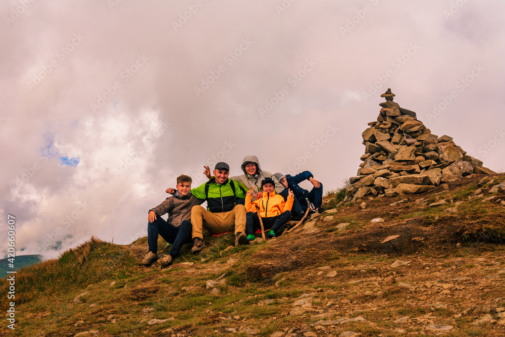 Obraz premium A group of tourists are sitting smiling on top of the mountains of the Montenegrin ridge, Mount Rebra is one of the peaks of the Carpathian mountains.