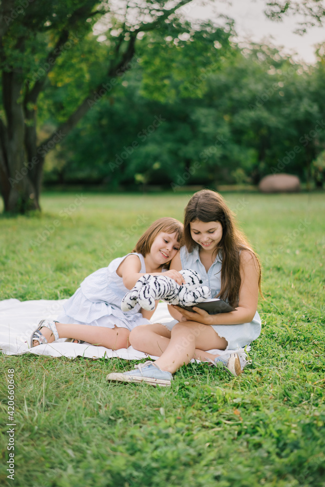 Happy sisters playing and reading book in park Happy sisters playing and reading book in park