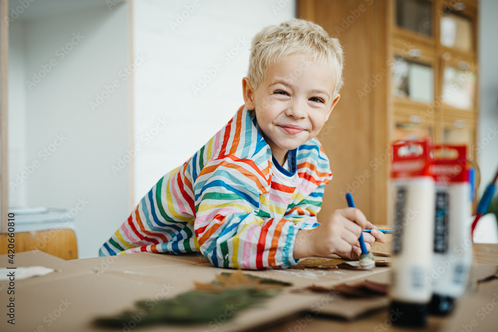 Little blonde boy playing with paint and autumn leafs Little blonde boy playing with paint and autumn leafs