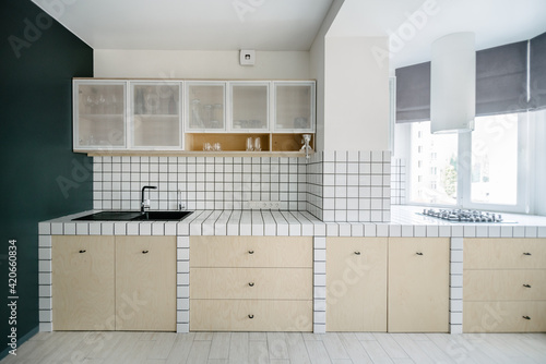 Kitchen in white tilles and a grey wall in a minimalist apartment photo