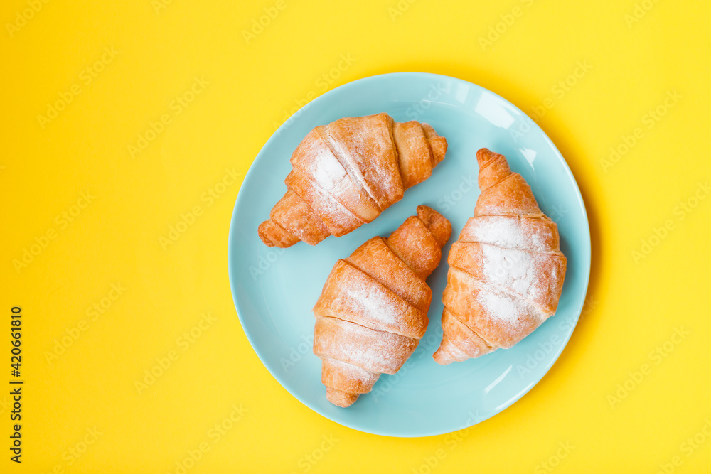 Cup of espresso coffee and croissant on yellow background, copy space