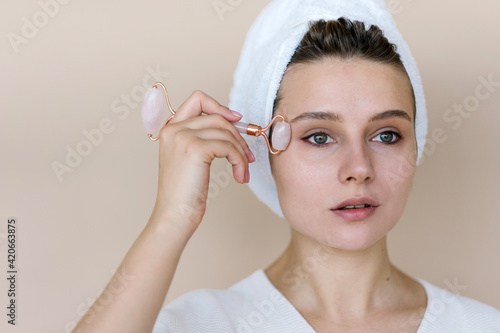 Woman treating skin with jade roller photo