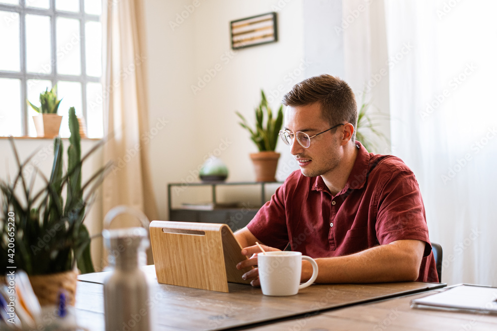 Young man browsing the tablet while taking a coffee Young man browsing the tablet while taking a coffee