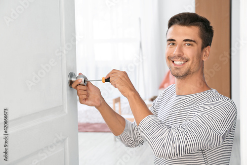 Young man repairing door lo...