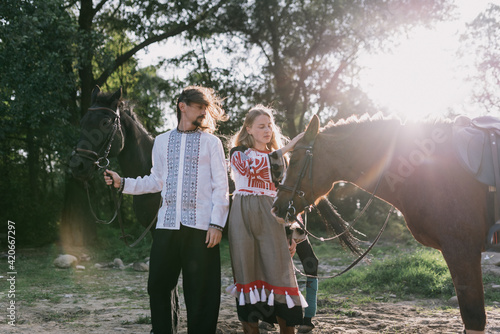 Young couple an two horses in a traditional costumes photo