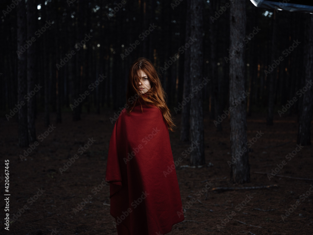 Beautiful woman with a red cape in the black forest at night Beautiful woman with a red cape in the black forest at night