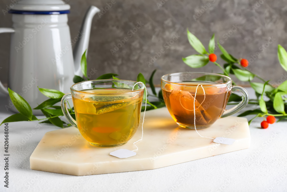 Cups of aromatic green and black tea on light background Cups of aromatic green and black tea on light background