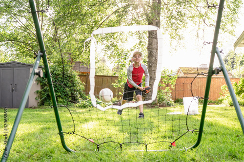 Boy throws baseball at rebounder photo