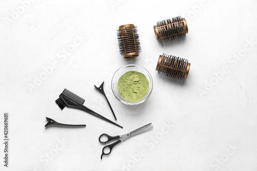 Bowl with henna and hairdresser's supplies on white background