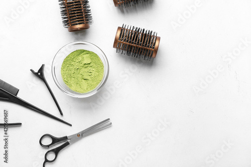 Bowl with henna and hairdresser's supplies on white background