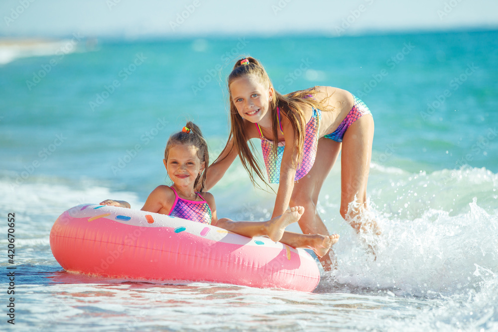 Obraz premium Children at sea play merrily. Two sisters run, jump on the beach in summer. High quality photo.