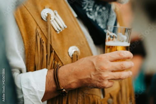 close up of a cowboy holding a glass of beer