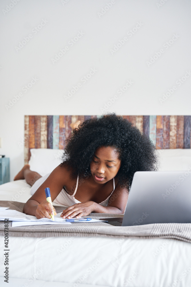 Black teenager doing homework on bed Black teenager doing homework on bed