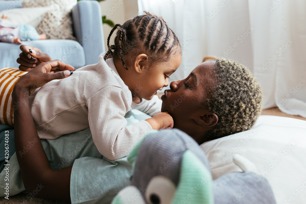Black mother and daughter kissing at home Black mother and daughter kissing at home