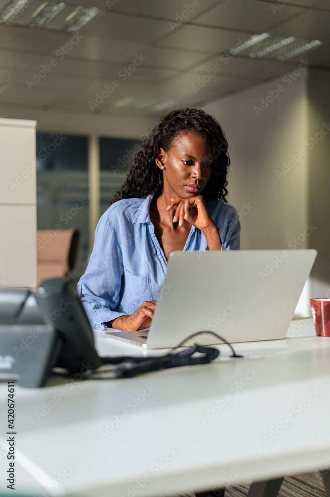 Serious black woman taking notes in planner during work in office Serious black woman taking notes in planner during work in office