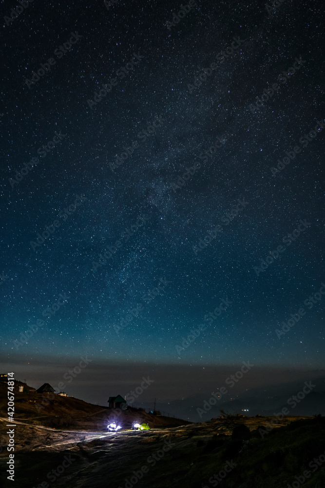 Fototapeta premium Illuminated tent in the night under the sky with many stars 