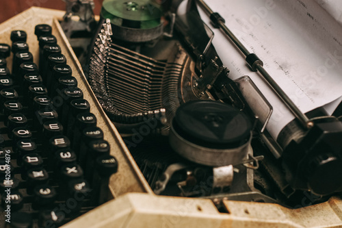 vintage typewriter with keys on a wooden background and a white sheet of paper