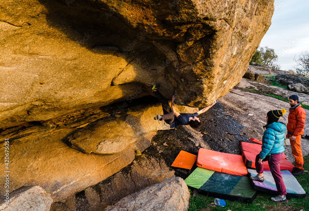 Man climbing granite boulder rock near friends Man climbing granite boulder rock near friends